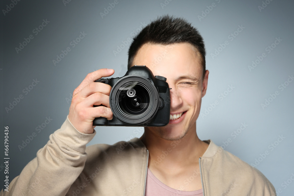 Handsome photographer with camera on gray background Handsome photographer with camera on gray background