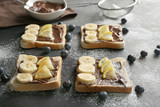 Delicious toasts with banana, chocolate spread and lemon on dark table