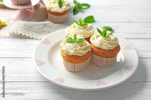 Plate with delicious carrot muffins on wooden table