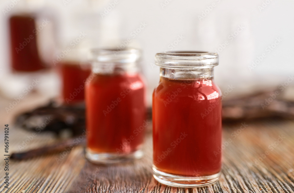 Bottle with vanilla extract on wooden table Bottle with vanilla extract on wooden table