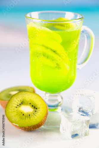 Tasty drink with kiwi on sandy beach