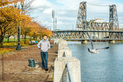 Man walking along the riverwalk in Portland city at autumn