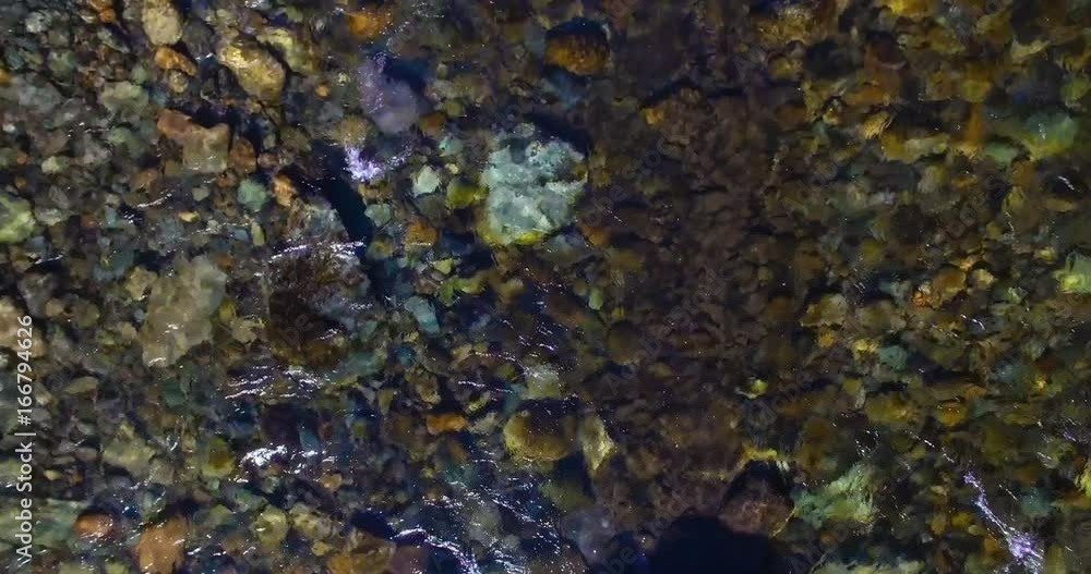 Aerial UHD 4K view. Mid-air flight over fresh and clean mountain river with transparent water and stone river bed at sunny summer morning. Top view and horizontal movement