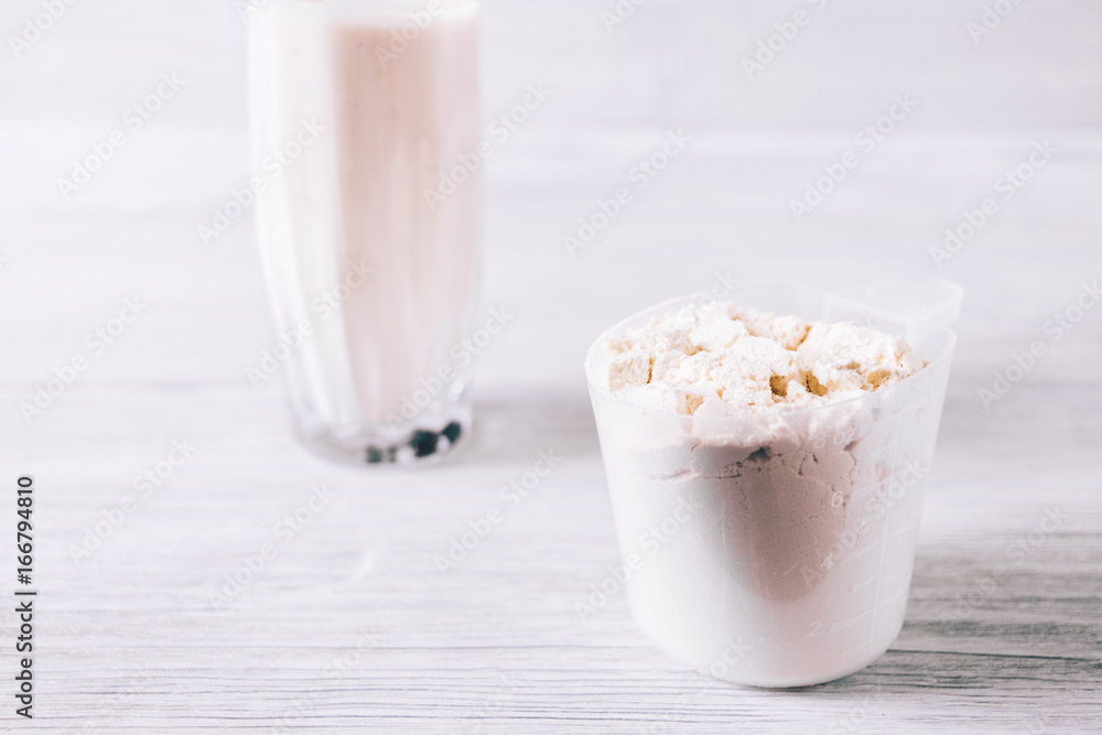 Protein powder in scoop on white wooden table Protein powder in scoop on white wooden table