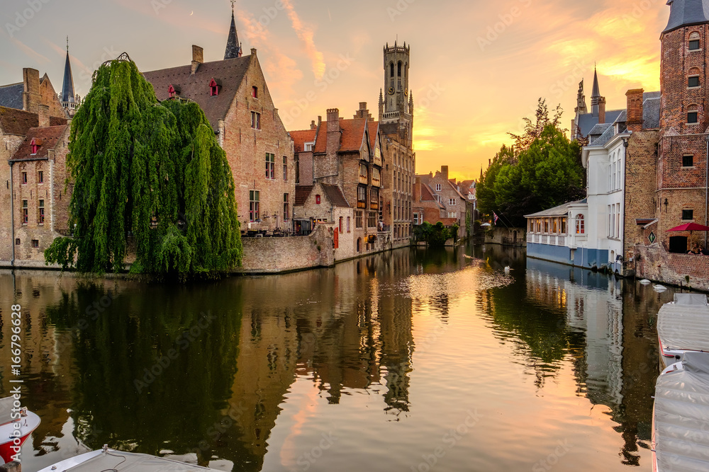 Fototapeta premium Miasto Brugia (Brugge) z kanałem wodnym o zachodzie słońca
