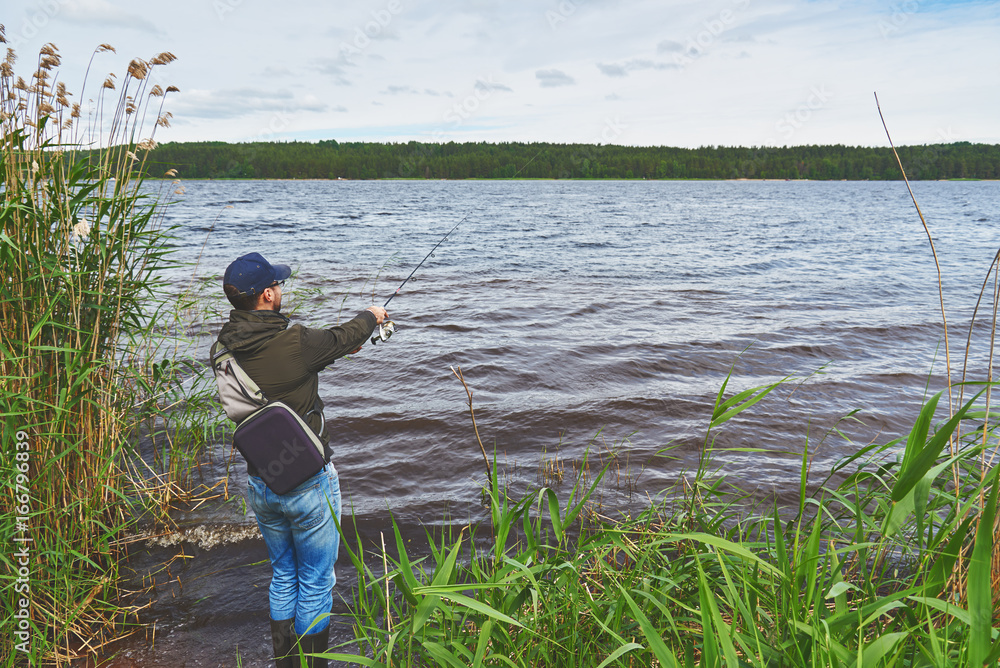 Man fishing bass with spinning rod in a lake.