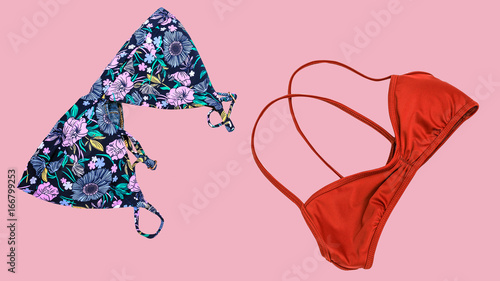 Summer vacation background, travel accessories costumes, bikini swimsuit with floral print and pink bikini woman clothes isolated on blue background