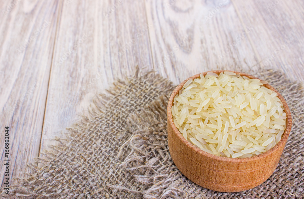 Jasmine Rice in bowl and burlap sack on wooden table Jasmine Rice in bowl and burlap sack on wooden table