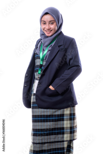 A beautiful, confident Muslim woman with a happy expression wearing hijab, suit and wearing a blank ID tag or name card on a lanyard holding cell phone isolated on white background.