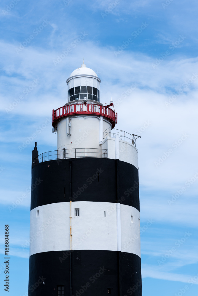 Top of a lighthouse with cloudy blue sky background