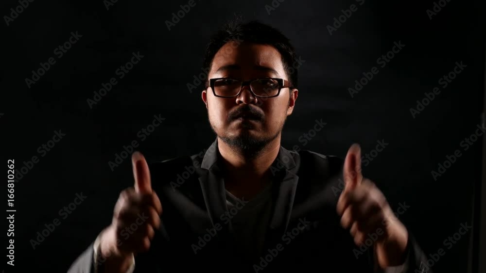 Hardwork sweating Serious Businessman in Black Suit showing thumbs up for good job on black wall background. Hardwork sweating Serious Businessman in Black Suit showing thumbs up for good job on black wall background.