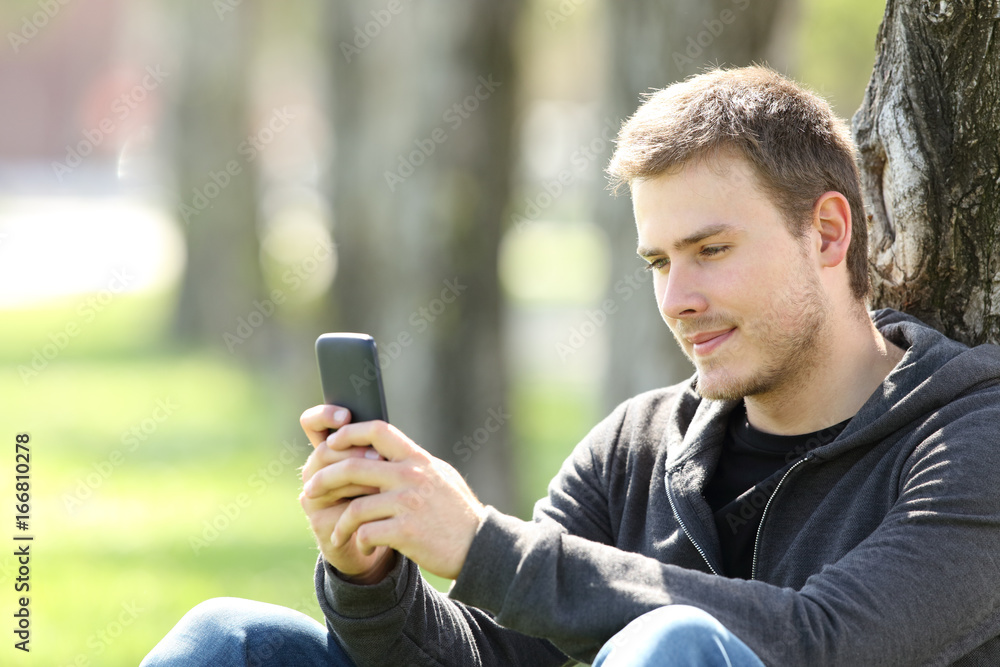 Boy reading messages in a smart phone outdoors Boy reading messages in a smart phone outdoors