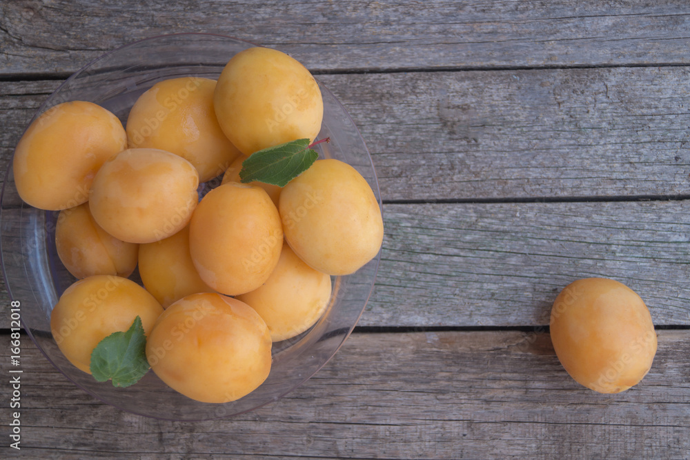 Ripe orange apricots in the plastic plate on grey wooden background