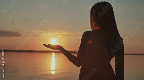 The young girl releases the sun from her hands. Beautiful romantic sunset.