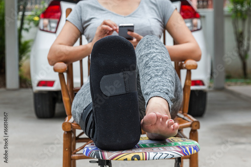 injury woman wearing sportsware with black cast on leg  sitting in white car, insurance concept photo