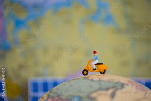 travel, journey, vacation concept. miniature people: woman ride motorcycle around the world.