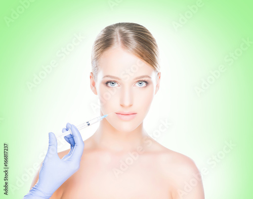 Young, beautiful and healthy woman having skin injections over green background. Plastic surgery concept.