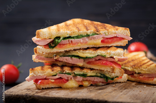 Club sandwich panini with ham, tomato, cheese and basil.