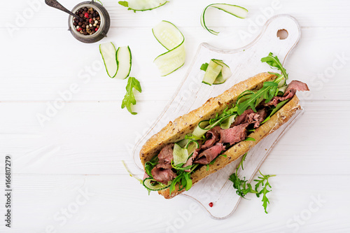 Sandwich of whole wheat bread with roast beef, cucumber and arugula. Top view. Flat lay