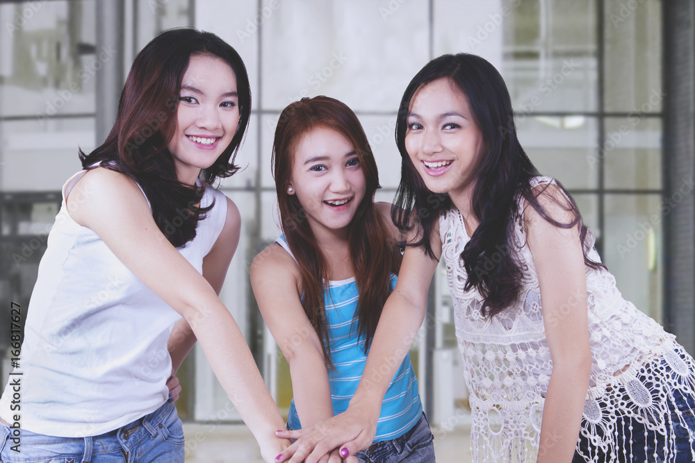 Asian female students joining hands together Asian female students joining hands together