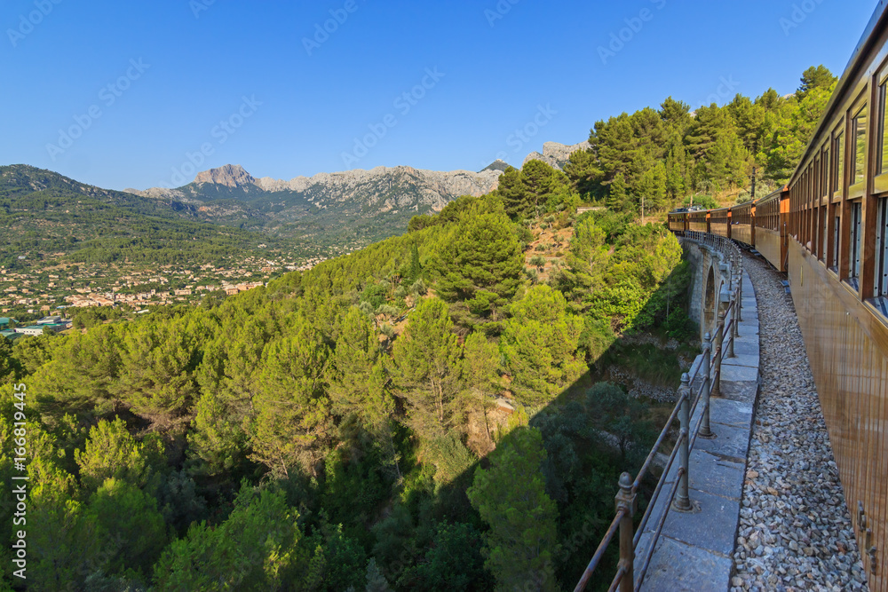 Crossing a viaduct on board a train between Soller and Palma with views over the village of Soller and the mountains range of the Serra de Tramuntana, Majorca Balearic Islands
