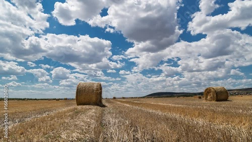 Field with bales of hay and beautiful sky time lapse