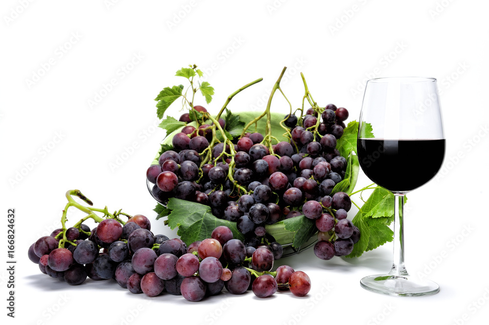 Wine glass and fresh red grape bunches photographed on a white background.