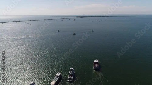 Aerial over Markermeer showing Marken in background flying forwards over squadron of tourist boats sailing in formation next to eachother towards Marken bird-eye view stable flight beautiful day 4k photo