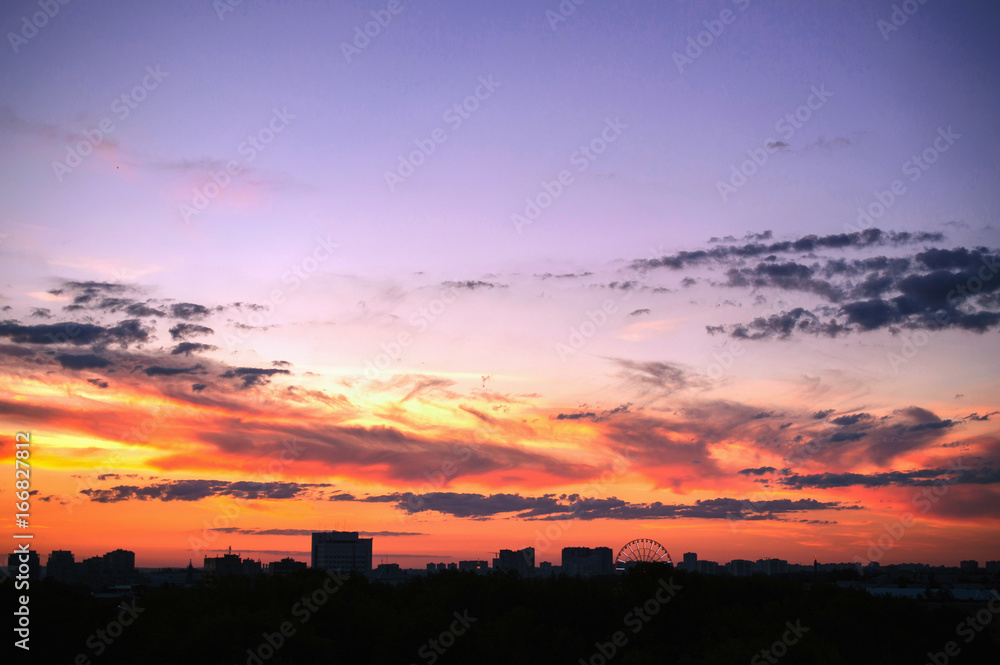 Clouds at sunset against backdrop of silhouettes houses a big ci