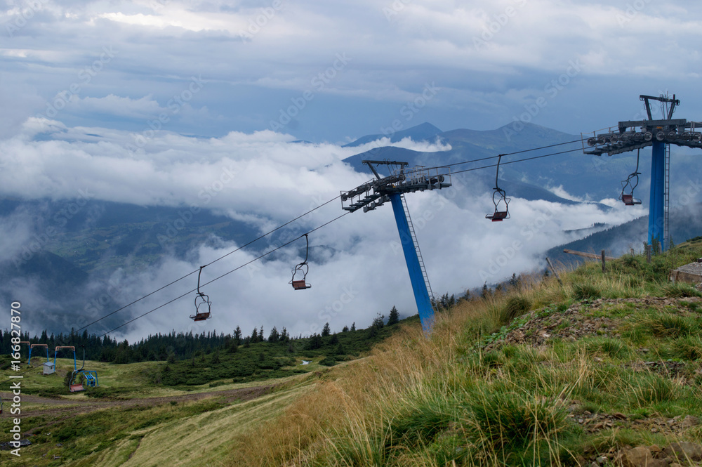 Chairlift in mountains on summer against the background of green