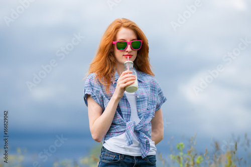Redhead skinny girl in sunglasses drinking milkshake 