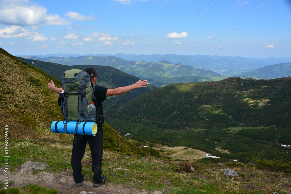 A tourist with a backpack stands on the background of the mountains