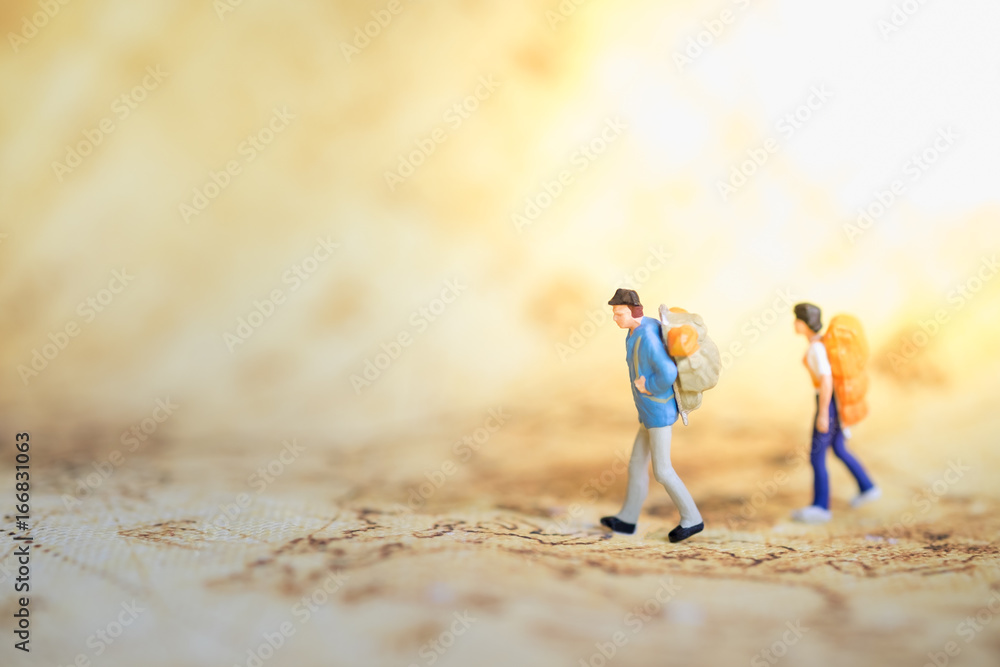 Fototapeta premium Two traveler miniature people figures with backpack standing and walking on world map. Travel and Journey concept.