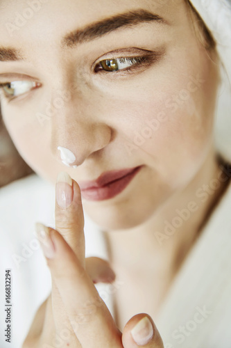 Junge Frau mit einem Klecks Hautcreme auf der Nase 