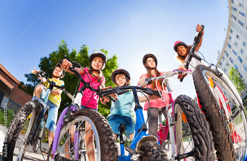Obraz premium Happy little bike riders standing against blue sky