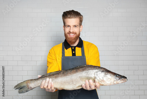 Seller holding fresh fish in supermarket
