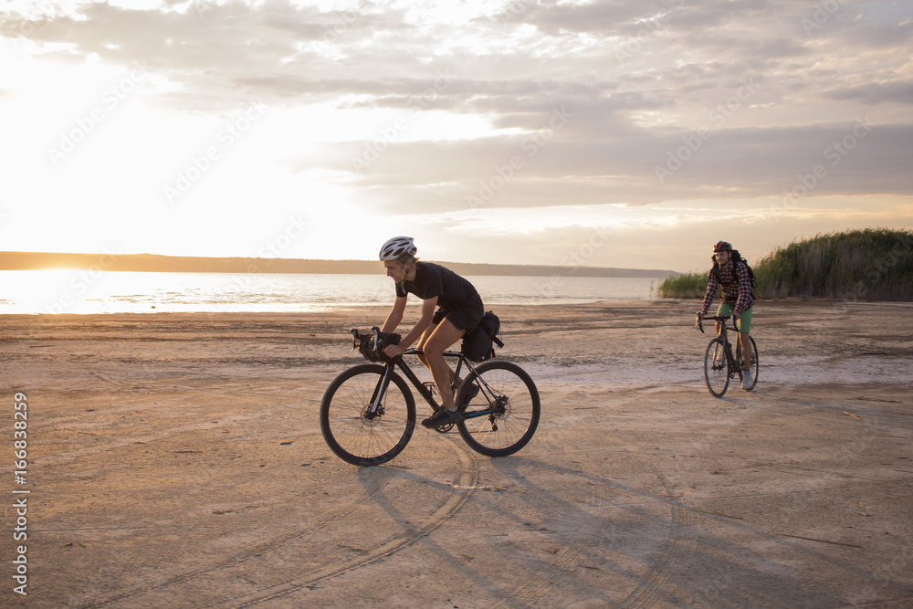 Fototapeta premium Twoo young male on a touring bicycle with backpacks and helmets in the desert on a bicycle trip 