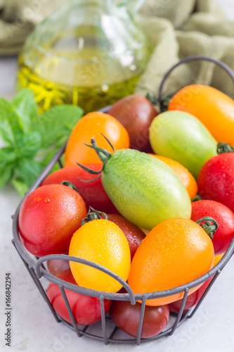 Fototapeta Naklejka Na Ścianę i Meble -  Small colorful cherry tomatoes in metal basket, vertical