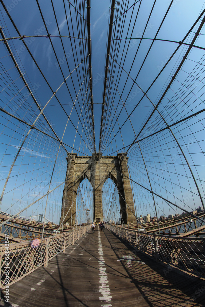 Fototapeta premium New York City: The Brooklyn bridge connecting the financial district of Manhattan island with Brooklyn is a famous landmark, popular tourist attraction and travel destination