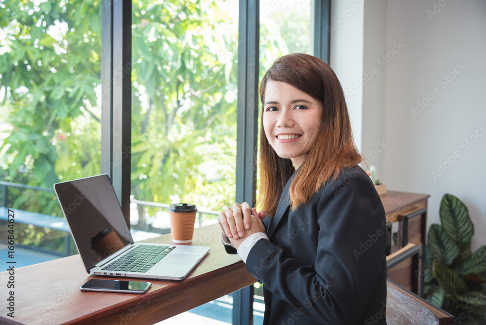 Beautiful young asian girl in suit smiling at camera between working Beautiful young asian girl in suit smiling at camera between working