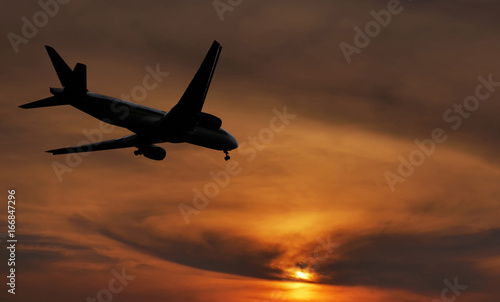Airplane is landing on sunset.