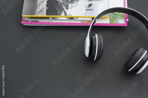 Headphones and magazine on black background.