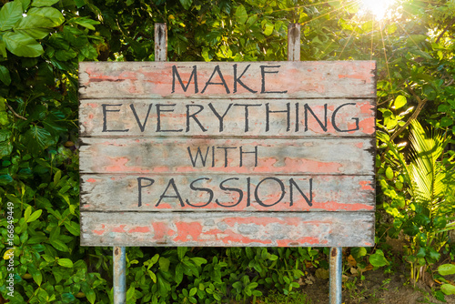 Make Everything with Passion motivational quote written on old vintage board sign in the forrest, with sun rays in background.