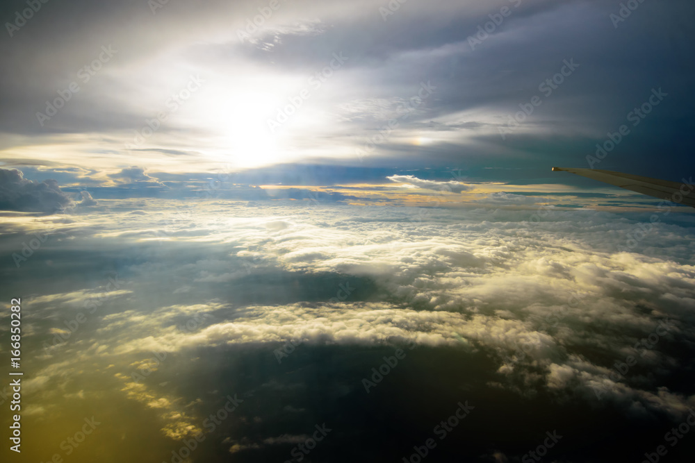 Fototapeta premium Beautiful sunset sky clouds seeing through the airplane windows. Sunset aerial view through airplane window over wings. Flying at sunset and looking out of the window and enjoying the panoramic view.