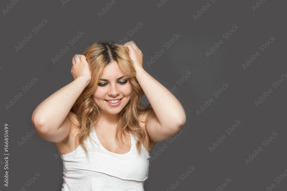 Smiling attractive long haired teenage girl with both hands in her hair