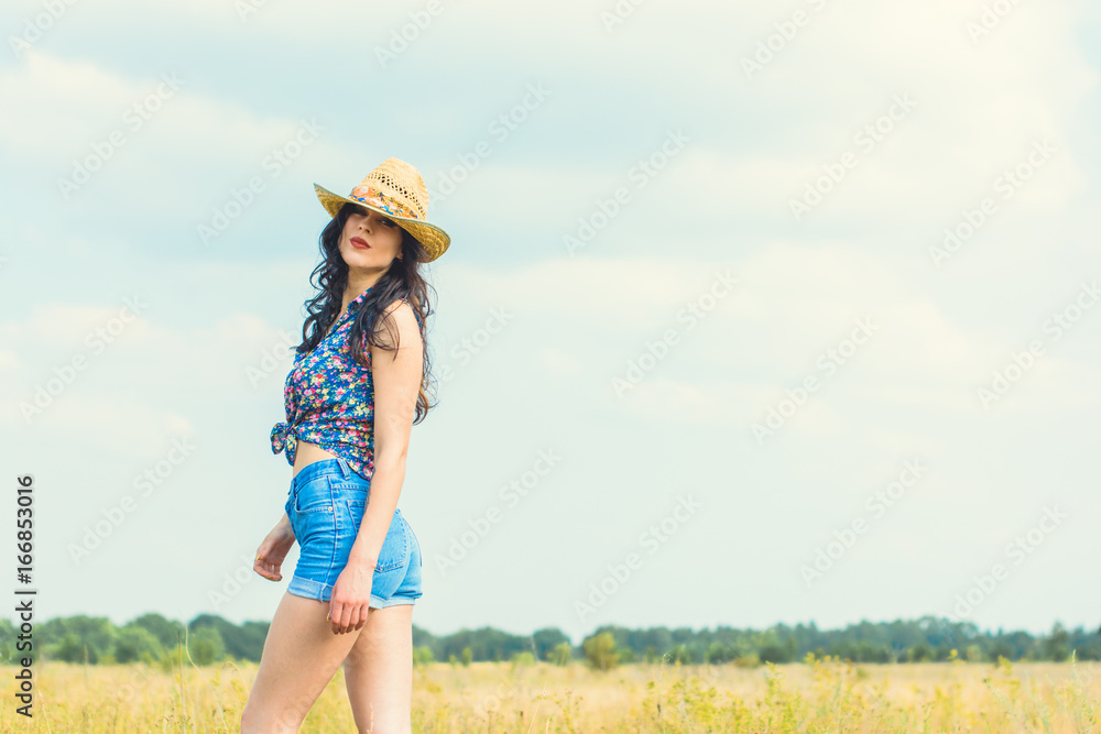 Woman in straw hat and american country style on a golden field feeling freedom