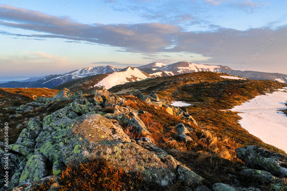 typical mountain landscape with stones rock in the foreground on the way snow covered valley at sunrise nature hiking