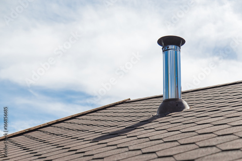Fotobehang Chimney pipe from stainless steel on the roof of the house