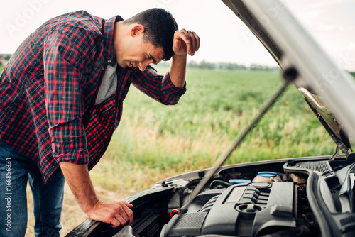 Tired man tries to repair a broken car