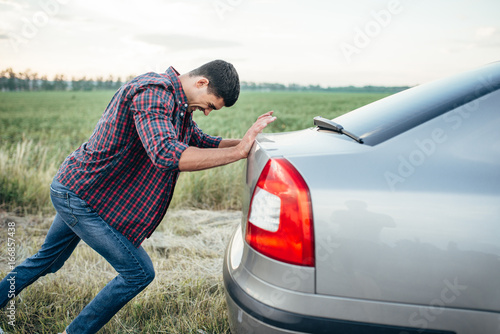 Plakat Man pushing broken car, side view